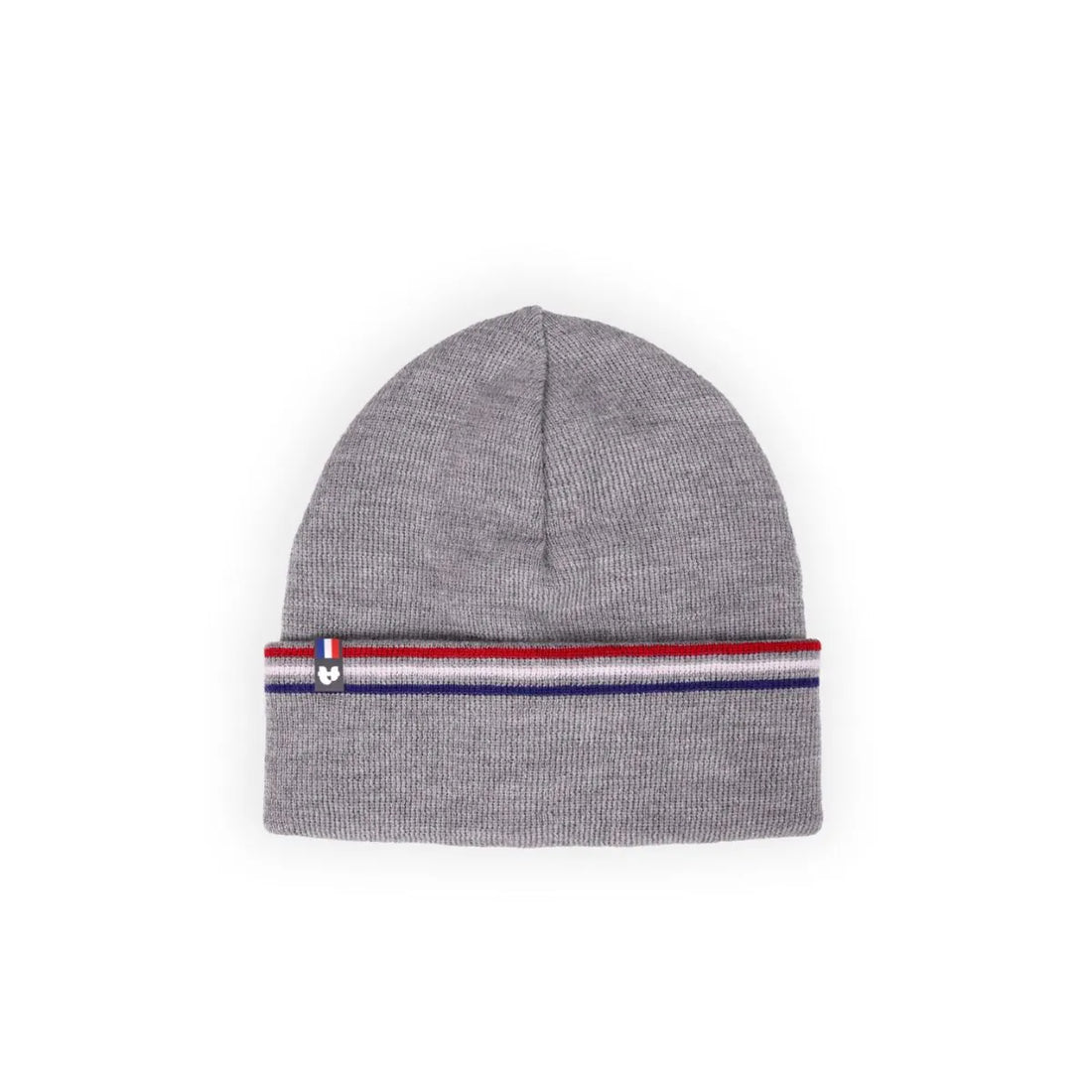 Femme souriante portant un bonnet en laine gris à revers rayé bleu-blanc-rouge, col roulé crème, dans les dunes – PALÂBA