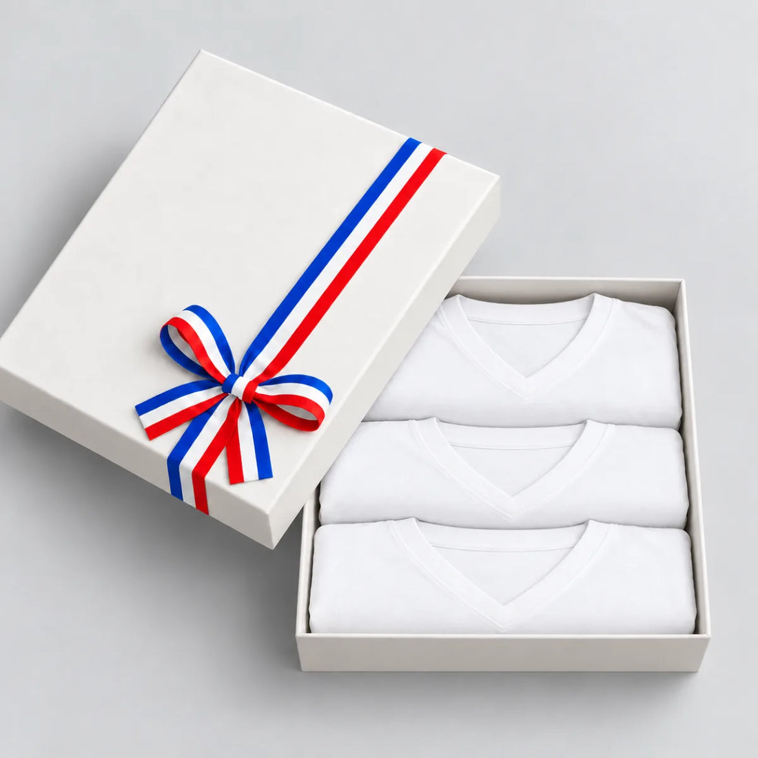 Coffret cadeau ouvert avec 3 t-shirts homme blancs col V en coton bio, ruban tricolore – PALÂBA
