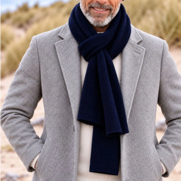 Homme en manteau gris portant une écharpe en cachemire et laine Marine Léman nouée sur un pull crème – PALÂBA