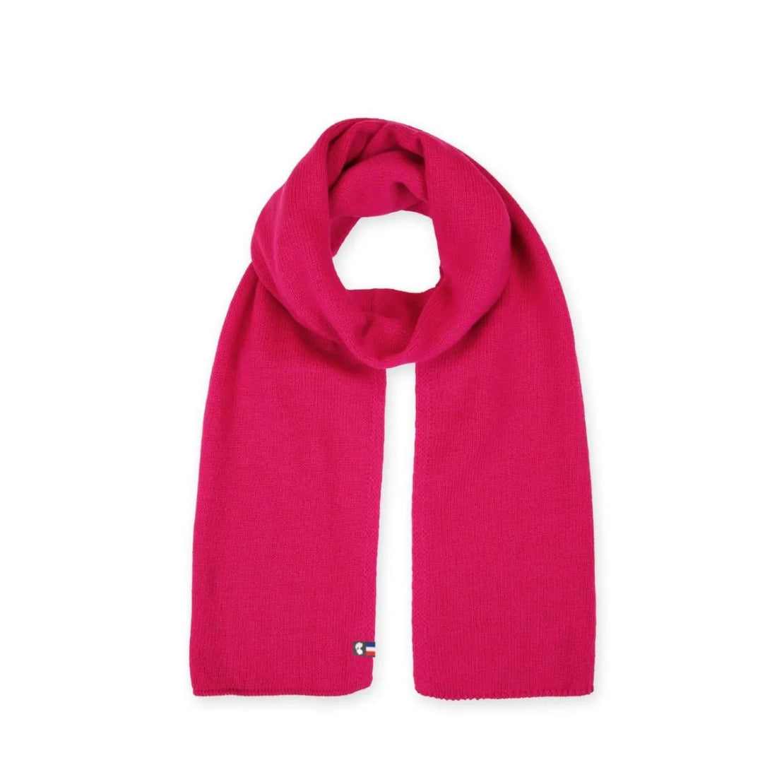 Femme en manteau beige portant une écharpe en laine mérinos Fuchsia Rosière nouée et les gants assortis, sur la plage – PALÂBA