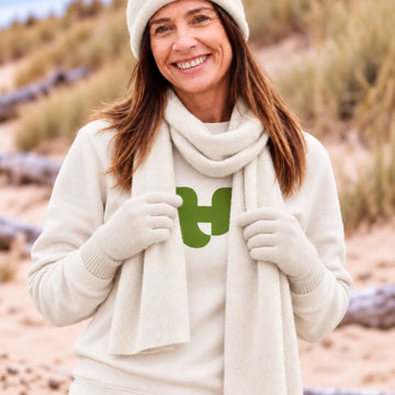 Femme portant le bonnet, l'écharpe et les gants en cachemire et laine Sable Vercors sur un sweat écru, dans les dunes – PALÂBA