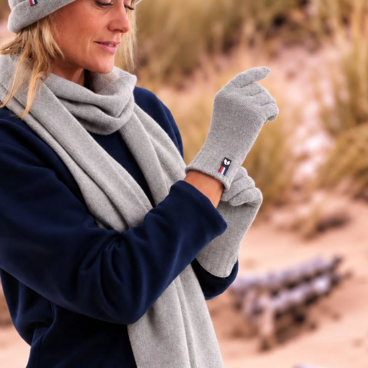 Femme enfilant des gants tactiles en cachemire et laine Gris Gavarnie, avec l'écharpe et le bonnet assortis – PALÂBA
