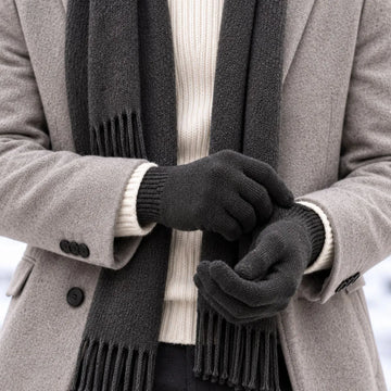 Homme en manteau gris clair et écharpe anthracite enfilant des gants tactiles en laine mérinos Roc Meije – PALÂBA