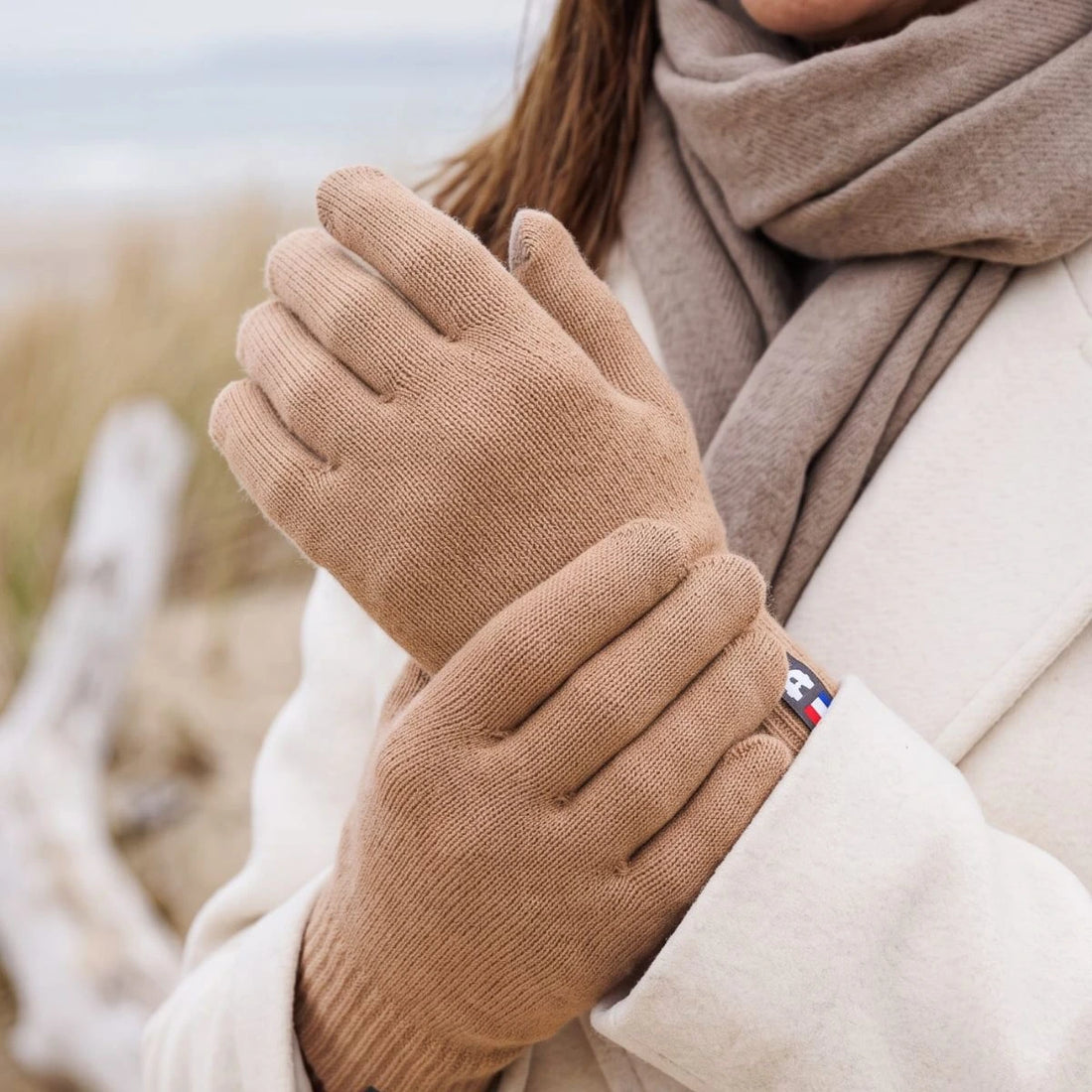 Gros plan sur les mains d'une femme portant des gants tactiles en laine mérinos Camel Aubrac – PALÂBA