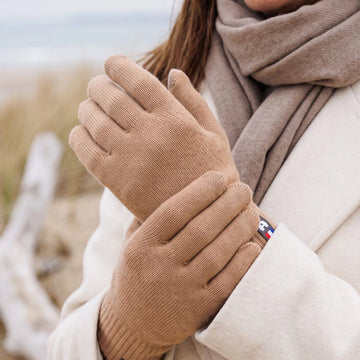 Gros plan sur les mains d'une femme portant des gants tactiles en laine mérinos Camel Aubrac – PALÂBA