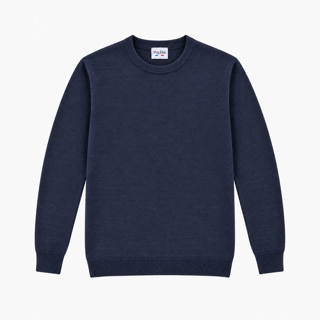 Homme portant le pull bleu marine en laine mérinos et un jean brut sur une terrasse au soleil – PALÂBA